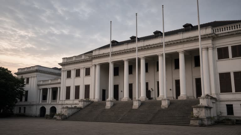 Colonial-era government building facade at dawn, flagpoles without readable flags, quiet empty steps, soft overcast light, no logos or readable text